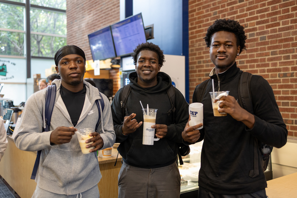 Three college students holding ice cream floats