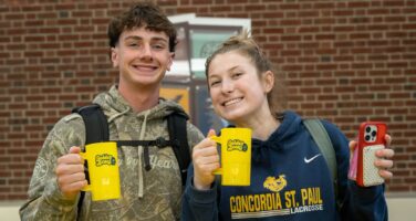 Two students with homecoming mugs
