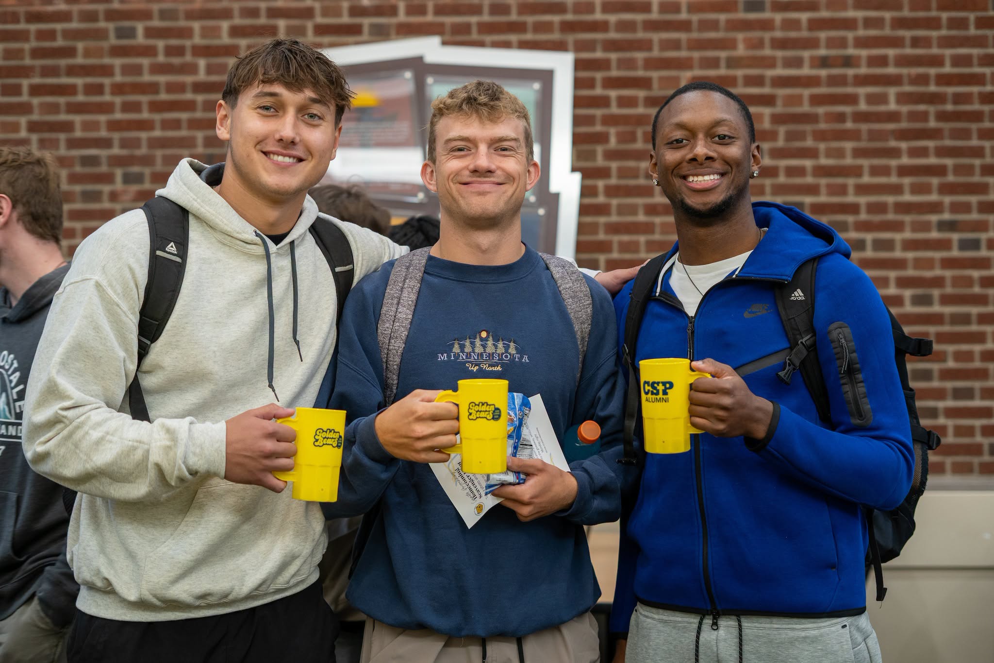 Three students with their homecoming mugs